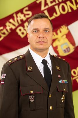 Pulkvežleitnanta Arvja Zīles portrets svētku formastērpā uz Zemessardzes 52. kaujas atbalsta bataljona karoga fona